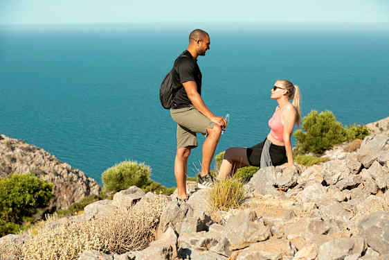 To personer tar en pause på en klippefull sti nær sjøen. (AI-generert tekst)