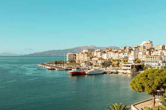 Utsikt over en by ved sjøen med småbåthavn og bygninger langs kysten. (AI-generert tekst)