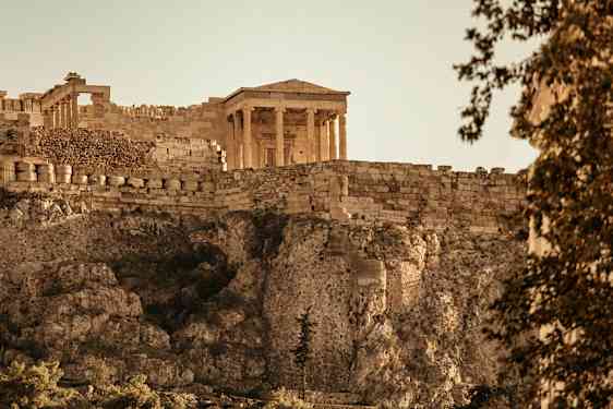 Et antikt tempel på Akropolis med steingjerde og klipper. (AI-generert tekst)