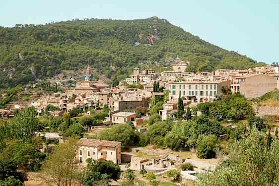 Bilde av en fjellandsby med flere steinhus omgitt av frodig vegetasjon. (AI-generert tekst)