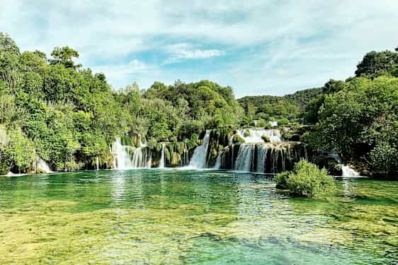 Et naturskjønt fossefall omgitt av frodig vegetasjon. (AI-generert tekst)