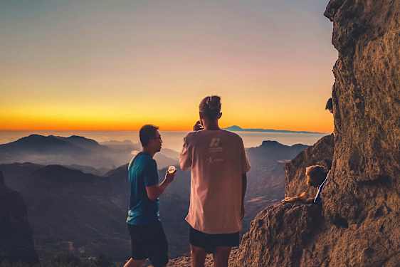 To personer ser på utsikten over fjellene ved solnedgang. (AI-generert tekst)