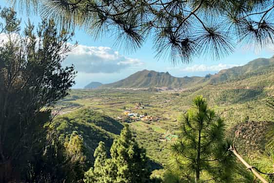 Utsikt over et grønt dalområde med landsbyer og fjell i bakgrunnen. (AI-generert tekst)