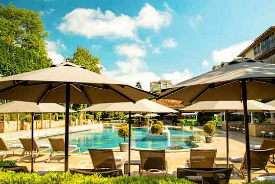 Bassengområde med parasoller, solsenger og omkringliggende grøntområder. (AI-generert tekst)