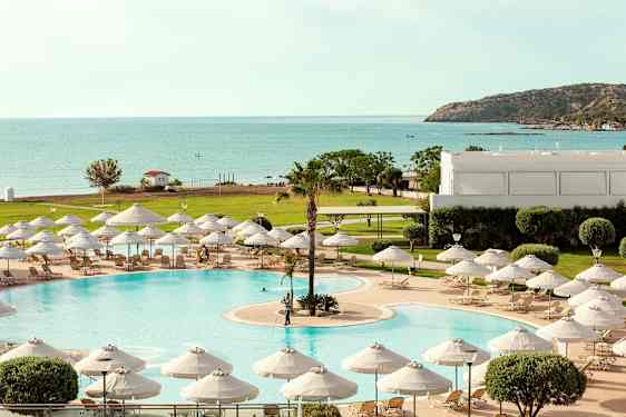 Et basseng med solsenger og parasoller, med utsikt mot havet og en frodig omgivelse. (AI-generert tekst)