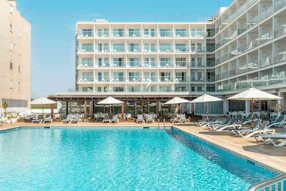 En bygning med flere balkonger, foran et basseng med solsenger og parasoller. (AI-generert tekst)