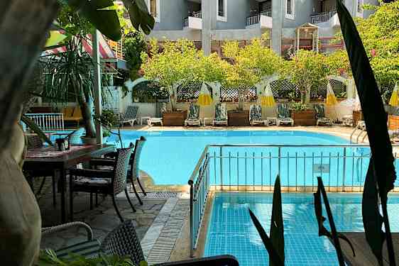 Et svømmebasseng med solsenger og parasoller i en hage. (AI-generert tekst)