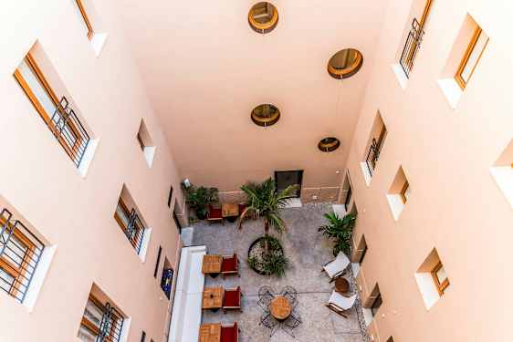 En indre gårdsplass sett ovenfra med bord, stoler og trær. (AI-generert tekst)