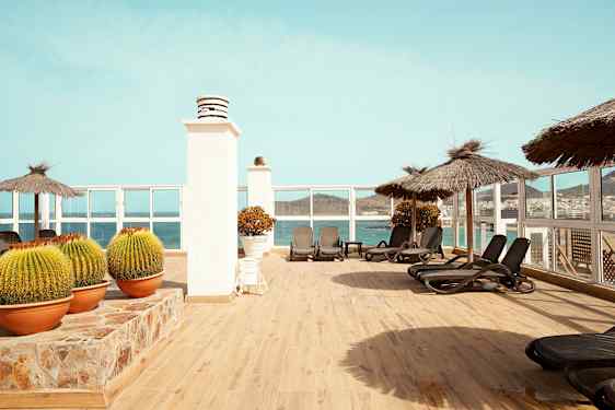 Terrasse med solsenger, parasoller og utsikt over havet. (AI-generert tekst)