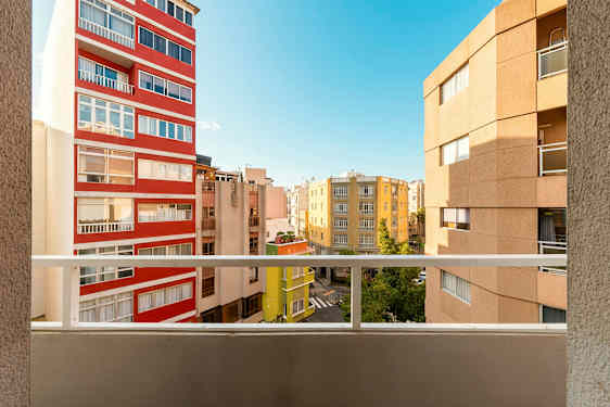 Utsikt fra en balkong med flere bygninger og en blå himmel i bakgrunnen. (AI-generert tekst)