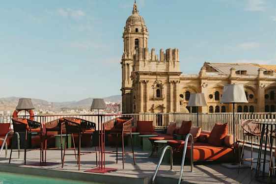 En takterrasse med basseng og loungemøbler, med en historisk bygning i bakgrunnen. (AI-generert tekst)