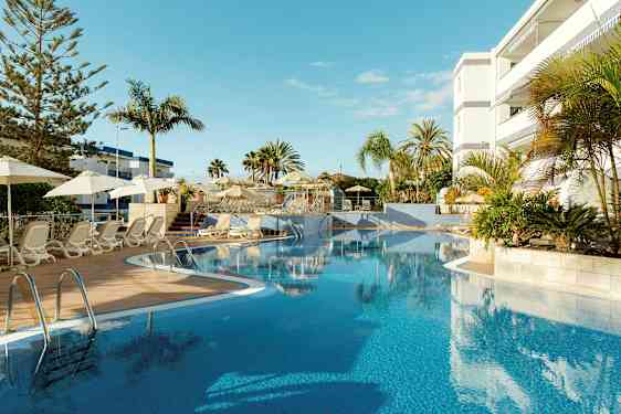 Utendørsbasseng med solsenger og parasoller ved et hotell. (AI-generert tekst)