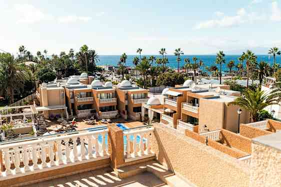 Utsikt over hotellbygninger og et basseng med havet i bakgrunnen. (AI-generert tekst)