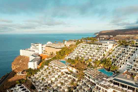 Hotellkompleks på en klippe med bassenger og havutsikt. (AI-generert tekst)