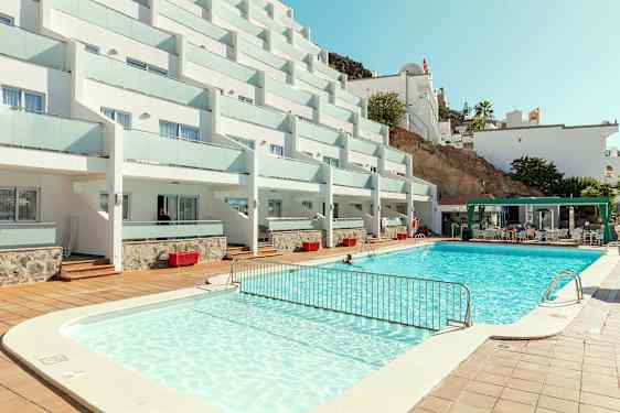 Bilde av hotellkompleks med basseng og sitteområde. (AI-generert tekst)