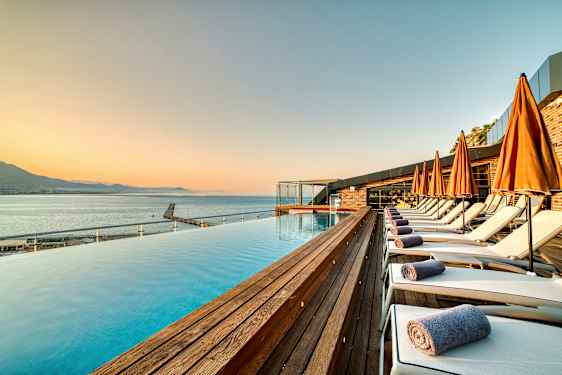 Strandnært bassengområde med solsenger og oransje parasoller. (AI-generert tekst)