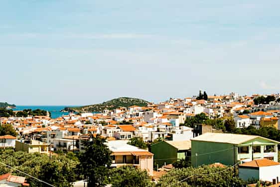 Panoramautsikt over en by med hvite bygninger og røde tak nær kysten. (AI-generert tekst)