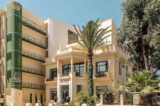 Bilde av en hotellbygning omgitt av palmer. (AI-generert tekst)