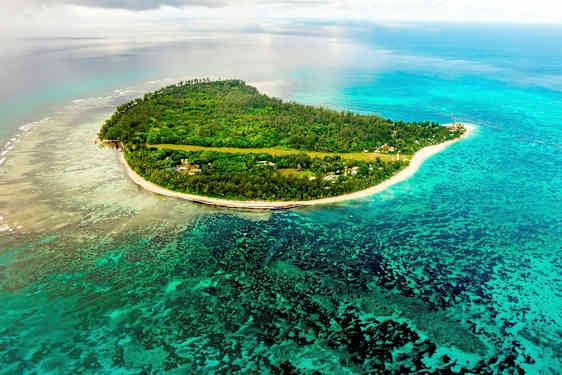 Luftutsikt over en tropisk øy omgitt av blått hav og korallrev. (AI-generert tekst)