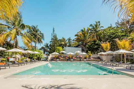 Et basseng omgitt av solsenger og parasoller med palmer i bakgrunnen. (AI-generert tekst)