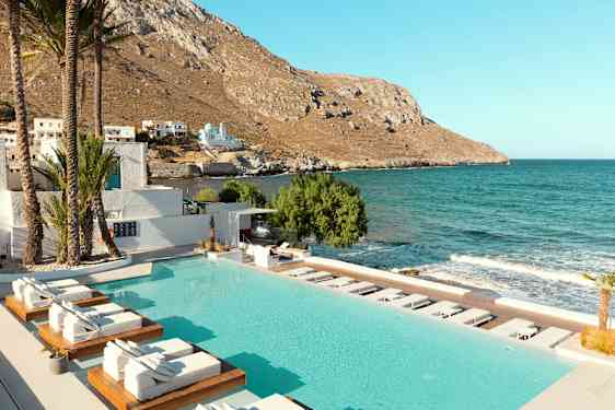 Bassengområde med solsenger nær havet og en fjellkyst. (AI-generert tekst)