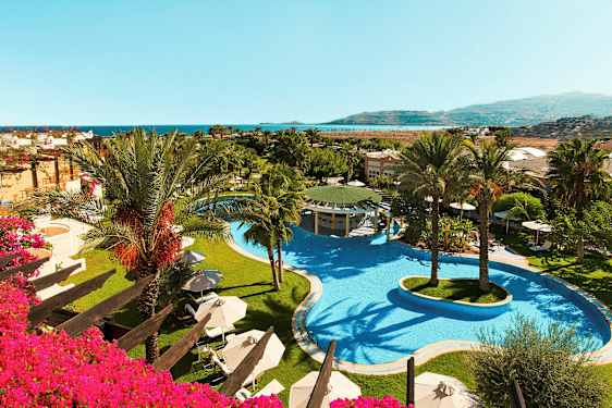 Bilde av hotellområde med et stort basseng og palmer, samt utsikt mot havet. (AI-generert tekst)