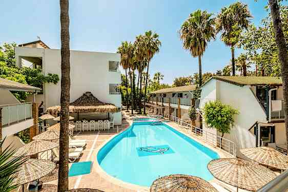 Utendørs basseng omgitt av hvite bygninger og palmer. (AI-generert tekst)