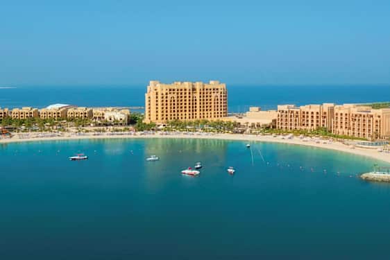 Hotellkompleks ved en sandstrand og en havbukt. (AI-generert tekst)