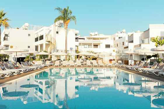 Basseng med solsenger og bygninger i bakgrunnen. (AI-generert tekst)