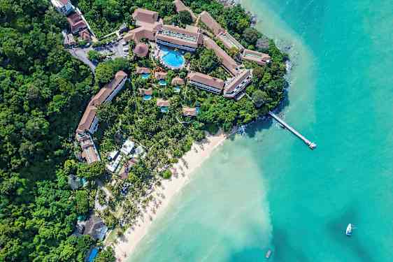 Flyfoto av en resort ved en sandstrand og turkist vann. (AI-generert tekst)