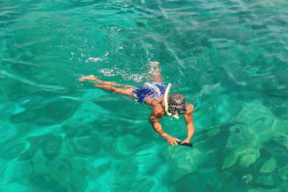 En person svømmer i klart vann med snorkelutstyr. (AI-generert tekst)