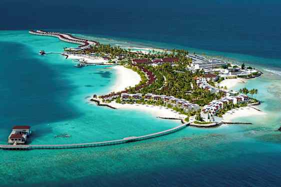 En øy med resortbygninger omgitt av turkis vann. (AI-generert tekst)