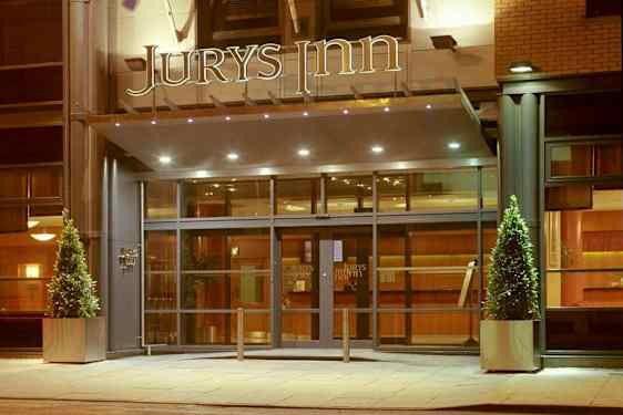 Hotellinngang med glassdører og skiltet 'Jurys Inn' over. (AI-generert tekst)