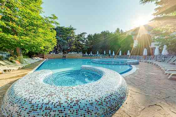 Utendørsbasseng med solsenger og trær i bakgrunnen. (AI-generert tekst)