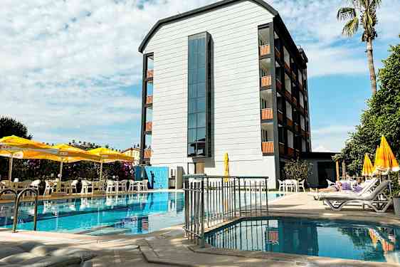 En bygning ved et basseng med solsenger og parasoller på terrassen. (AI-generert tekst)