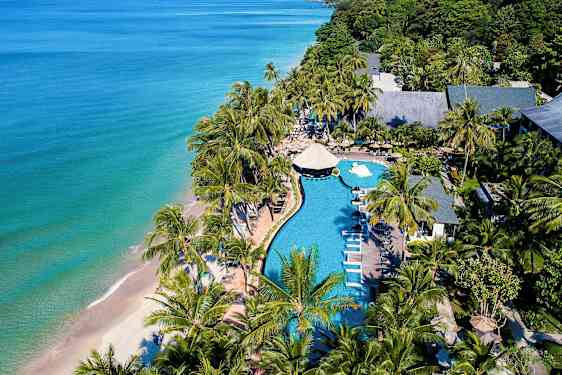 Utsikt fra luften over et strandresort med basseng, solsenger og palmer ved havet. (AI-generert tekst)