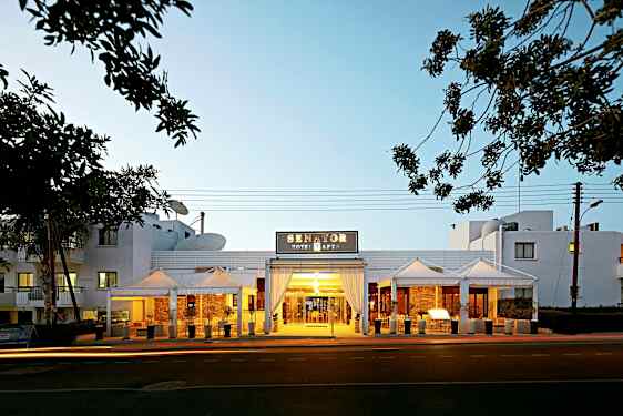 Inngangen til Senator Hotel Apartments med kveldsbelysning. (AI-generert tekst)