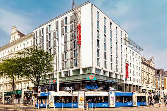 En flerfarget trikk foran et moderne hotell i bymiljø. (AI-generert tekst)