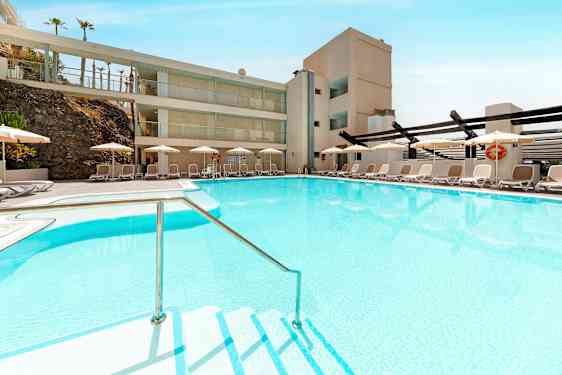 Et basseng med klart blått vann omgitt av solsenger og parasoller. (AI-generert tekst)