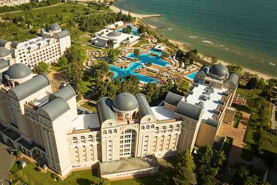 Oversiktsbilde av et hotellkompleks med bassenger og strand. (AI-generert tekst)