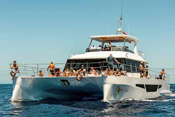 En hvit motorbåt på havet med mennesker som nyter solen. (AI-generert tekst)