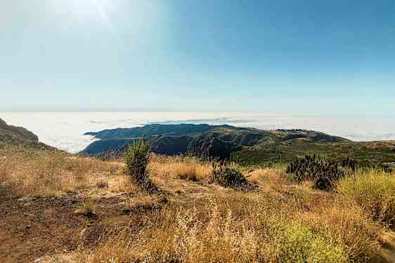 Solrik fjellutsikt med skyet panorama og tørr vegetasjon. (AI-generert tekst)