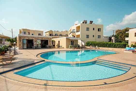 Et bilde som viser et utendørsbasseng omgitt av solsenger og bygninger i bakgrunnen. (AI-generert tekst)