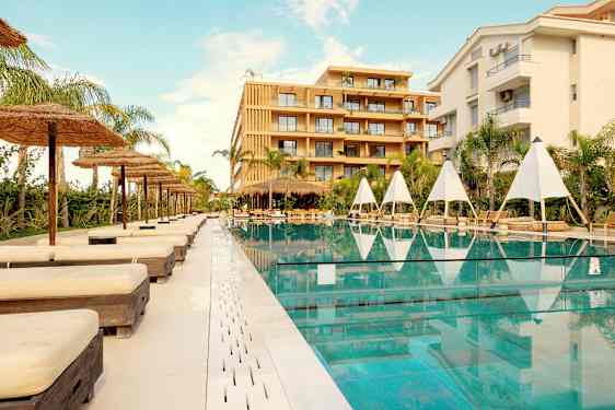 Utendørs svømmebasseng med solsenger og parasoller ved et hotell. (AI-generert tekst)