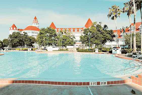 Bilde av et basseng med et elegant hvitt hotell med røde tak i bakgrunnen. (AI-generert tekst)