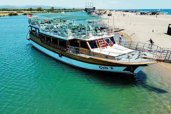 En båt ligger ved en brygge nær stranden. (AI-generert tekst)