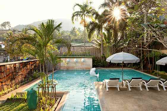 Et solbelyst basseng omgitt av palmer og solsenger. (AI-generert tekst)