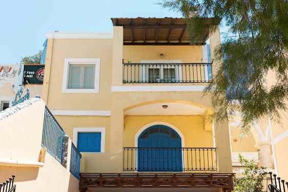 Gult hus med blå dører og balkonger. (AI-generert tekst)