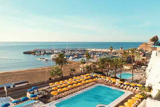 Utsikt over et basseng og en strand med en havn i bakgrunnen. (AI-generert tekst)