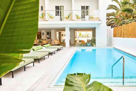 Utendørs svømmebasseng ved hotell med solsenger og frodige omgivelser. (AI-generert tekst)